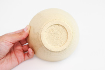 beige clay plate in hand on a white background. minimalism style. handmade