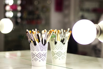 a cup of coffee and a make-up brush on the wizard's table in the backlight on a glass surface with blemishes