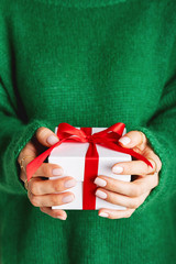 Female in woolen green sweater holding a present red gift box with a bow. Christmas festive layout....