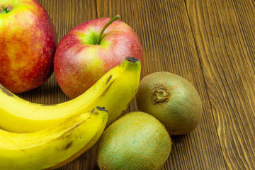 Close up view of red apples, bananas and kiwi on wooden background. Still life of fresh fruits