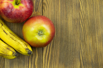 Fresh fruits. Close up view of red apples and bananas on wooden background with copy space for text