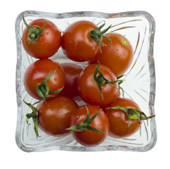 Top view of fresh red cherry tomatoes with a water drops in a glass bowl isolated on a white background.