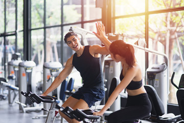 Healthy woman and man with sportswear running giving each other a high five while training on exercise at gym sport, bodybuilding, lifestyle and people concept