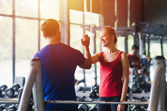 Fitness woman and man with sportswear giving each other a high five while training on exercise at gym sport, bodybuilding, lifestyle and people concept