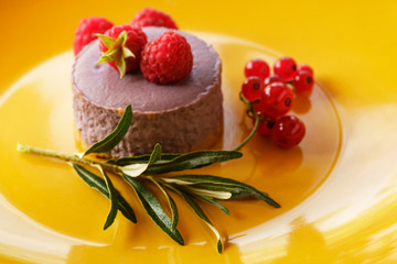 Tasty dessert cheesecake with raspberries and currants on a yellow background. 