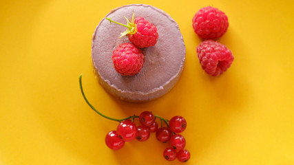 Tasty dessert cheesecake with raspberries and currants on a yellow background. Flat lay food