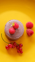 Tasty dessert cheesecake with raspberries and currants on a yellow background. Flat lay food