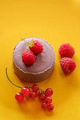 Tasty dessert cheesecake with raspberries and currants on a yellow background. Flat lay food
