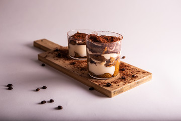 Italian tiramisu mono portion on wooden cutter board. White background