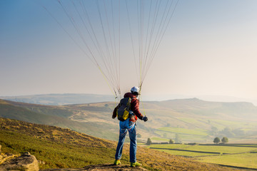 Obraz premium A man paragliding over the Stanage Edge in Derbyshire.