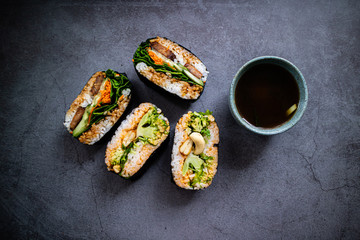 Seitan onigirazu and broccoli onigirazu with miso soup on concrete background. Japanese cuisine. Top view.