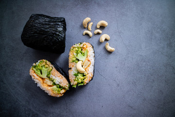 Vegan onirigazu with broccoli, cilantro, cashew and curry sauce on concrete background. Top view.