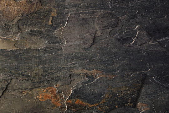 Textured dark slate stone background with natural minerals