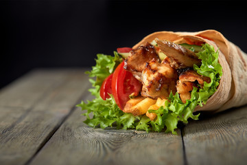 Chicken fajita wrap sandwich. Sandwich with fajita chicken. Roll with chicken meat fresh tomatoes and cucumbers, lettuce wrapped in bread pita. - obrazy, fototapety, plakaty