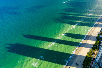 Aerial photo of skyscraper shadows in the ocean and beach