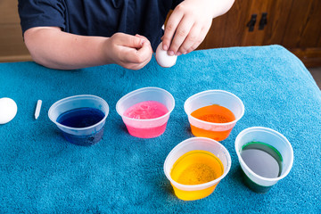 Child preparing to dip the easter egg for dyeing