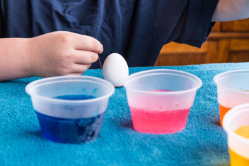Child preparing to dip the easter egg for dyeing