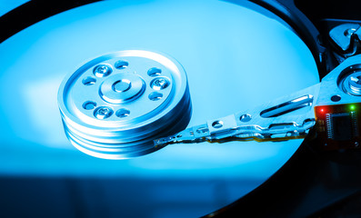 Close up inside of hard disk drive. Detail of writing/reading head on acuator arm and axis. Blue Toned Image.