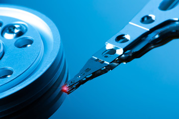 Close up inside of hard disk drive. Detail of writing/reading head on acuator arm and axis. Blue Toned Image.