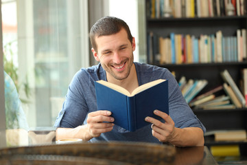 Happy reader reading a paper book in a coffee shop