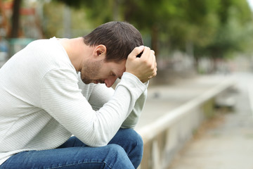 Sad adult man complaining alone in a park