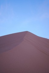 Fototapeta na wymiar Purple sand dune in the desert at dusk, a few minutes after sunset.
