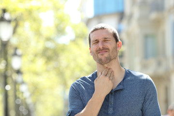 Stressed man suffering throat ache in the street
