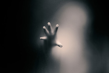 Black color version of Creepy man holding the frosted glass with one hand. - obrazy, fototapety, plakaty