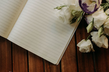 white flowers and notebook on a wooden table
