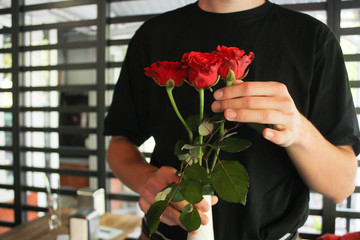 guy in a black t-shirt holds red roses