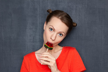 Fototapeta premium Portrait of cute flirty young woman enjoying lollipop taste