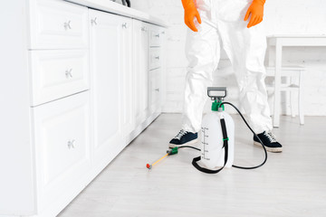 cropped view of man in uniform standing near toxic equipment in kitchen