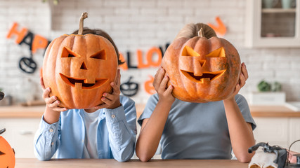 Two little kids celebrating Halloween at home kitchen