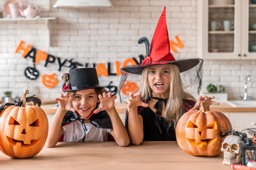 Childrens in suits and with pumpkins having fun on Halloween in the home kitchen