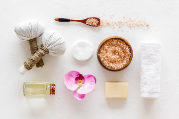 Massage table with thai herbal balls and orchids on white background top view pattern
