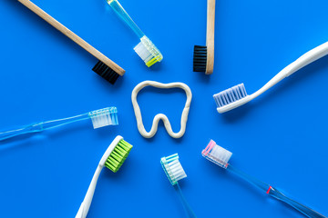 Oral hygiene concept. Tooth drawn with toothpaste near toothbrushes on blue background top view