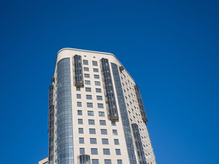 Fototapeta na wymiar Modern high-rise building on a background of blue sky. Theme of modern geometric architecture and urbanization