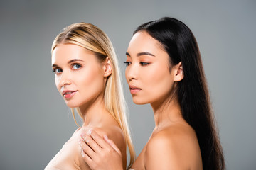 side view of beautiful european blonde and asian brunette naked women isolated on grey