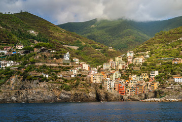 Fototapeta na wymiar Riomaggiore, Cinque Terre, Italy - August 17, 2019: Village by the sea bay, colorful houses on the rocky coast. Nature reserve resort popular in Europe.