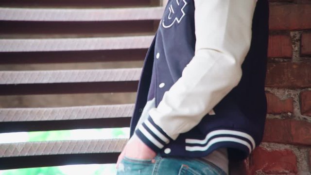 Tilt-up out of focus from shoes to hands in pockets 4K. Long shot tilt-up refocus to person hands in pockets. Male person wearing trendy clothes.