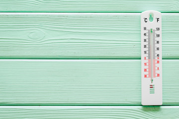 Weather thermometer on green wooden background top view copy space