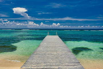 A beautiful wood dock leads out to the crystal clear and turquoise waters of the Cayman Islands in...