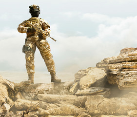 Soldier standing on desert rocks.