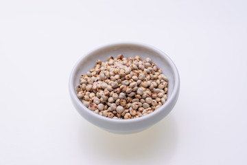 Uncooked raw Sorghum (also known as sorgo) in a white bowl, isolated on white background