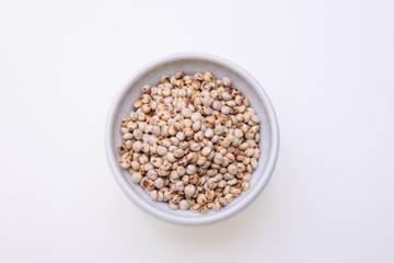 Uncooked raw Sorghum (also known as sorgo) in a white bowl, isolated on white background