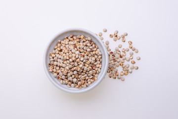 Uncooked raw Sorghum (also known as sorgo) in a white bowl, isolated on white background