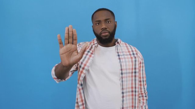 Portrait shock and annoyed displeased young man raising hands up to say no stop right there isolated blue background. Negative human emotion, facial expression, sign, symbol, body language 4K