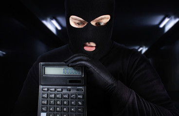 Male thied in mask holding calculator.