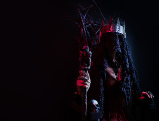 Female witch queen sitting on throne made of branches.
