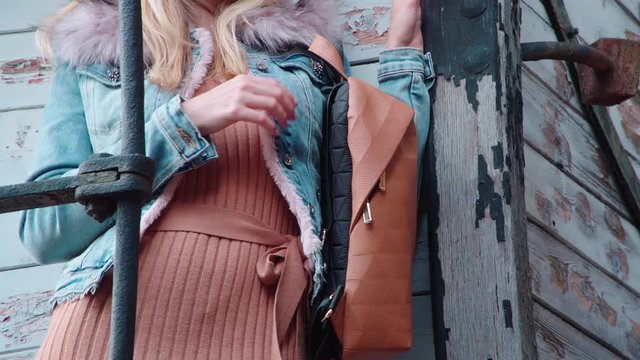 Female person posing with a handbag 4K. Long shot of person upper torso in focus holding a brown handbag.